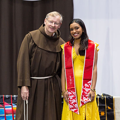 Photo of a graduating student standing with a monk. Gifts of Cash, Checks, and Credit Cards